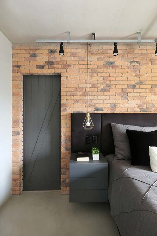 quarto decorado com parede de tijolinho e cabeceira estofada preta com criado mudo cinza Foto Pinterest
