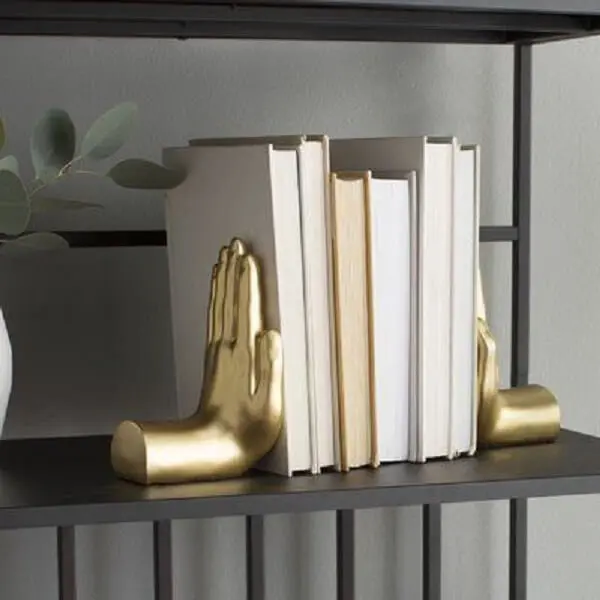 As mãos douradas se destacam na estante e servem como aparador de livros
