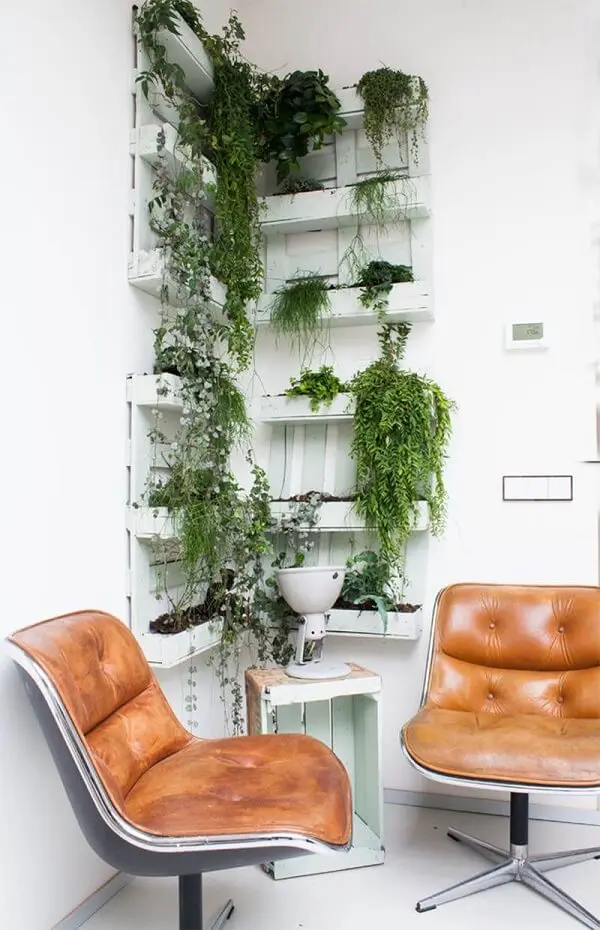 Floreira vertical de parede feita com pallets decoram o cantinho do escritório