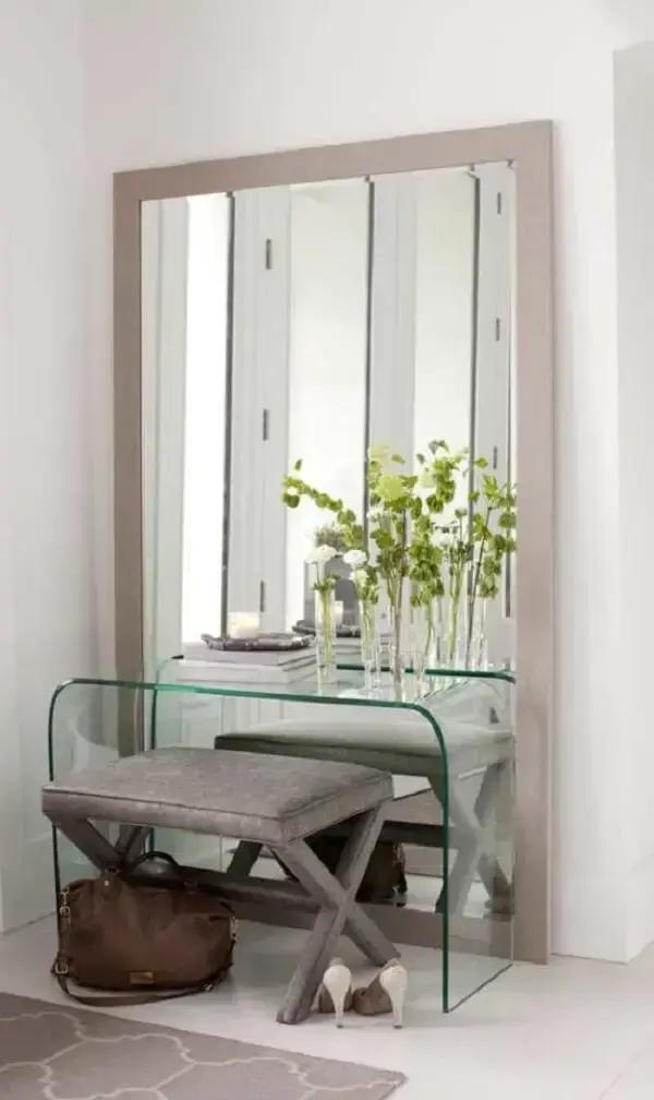 Hall de entrada sofisticado com aparador de vidro e espelho grande de chão. Fonte: Decor Fácil