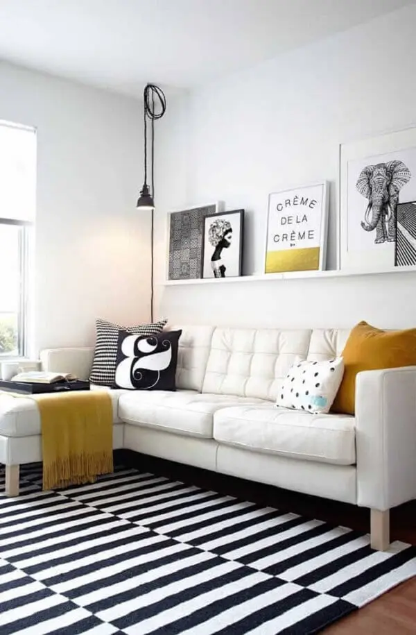 Quadros para sala de TV com sofá branco de canto e tapete listrado preto e branco