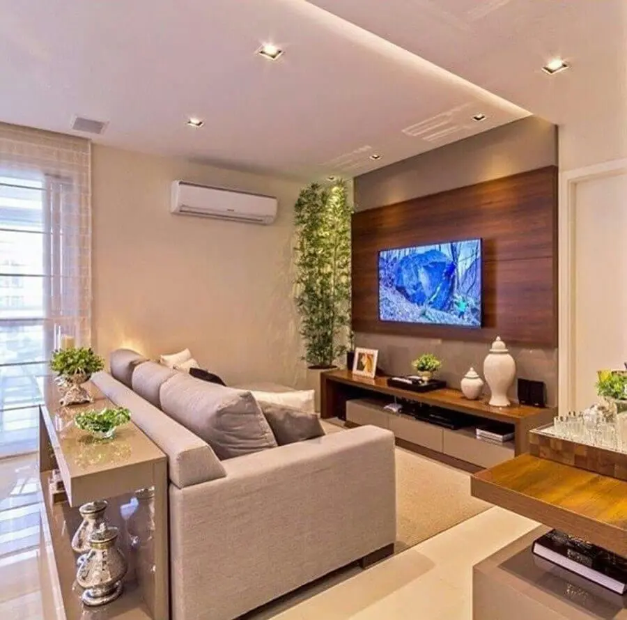 TV na parede da sala com painel de madeira e sofá cinza Foto Pinterest