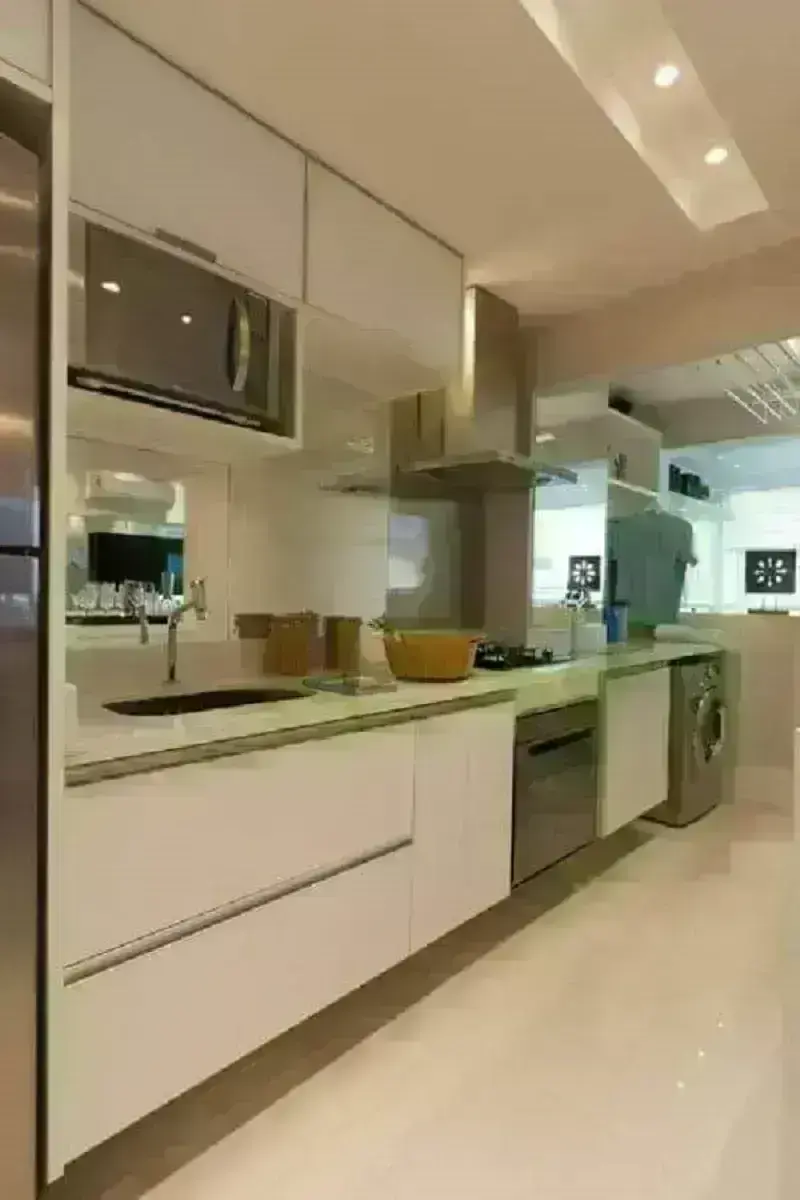 Cozinha planejada de apartamento pequeno com lavanderia em tons claros