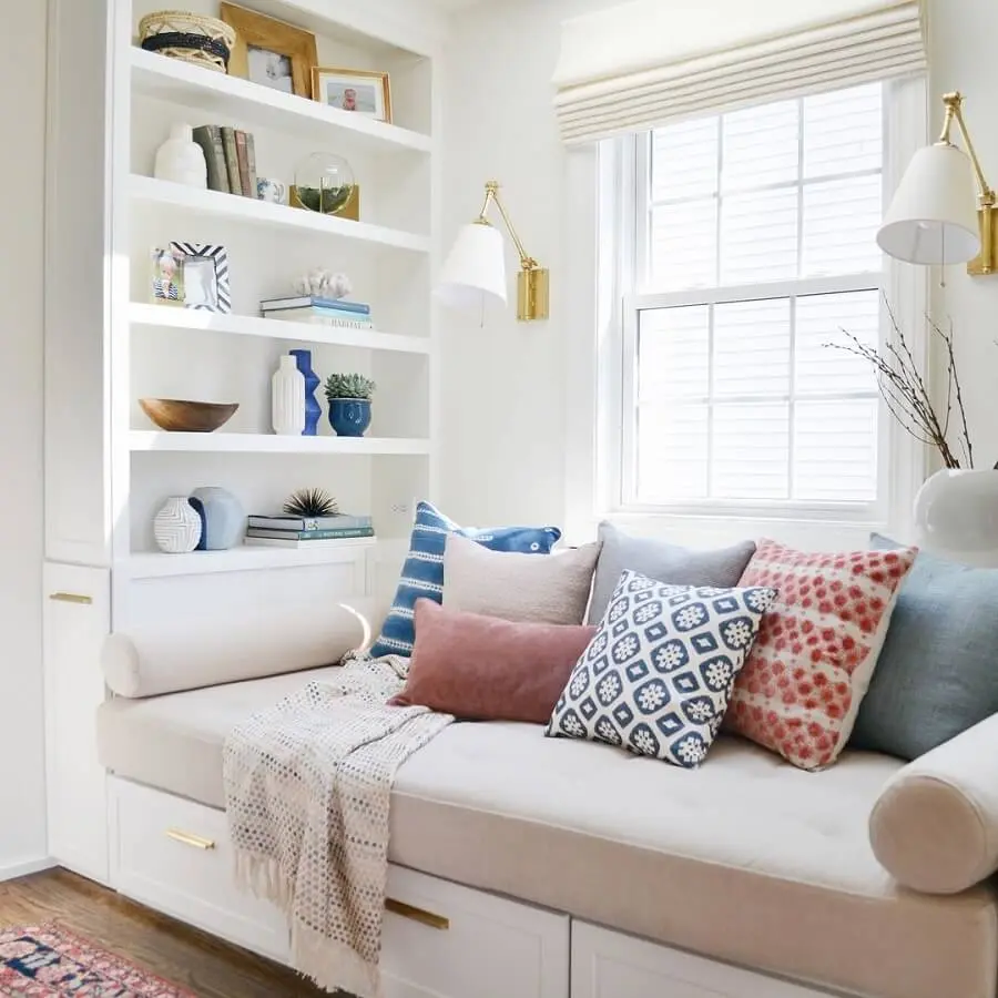 Cantinho de leitura confortável decorado com várias almofadas e luminária de parede para leitura - Foto: Pinterest