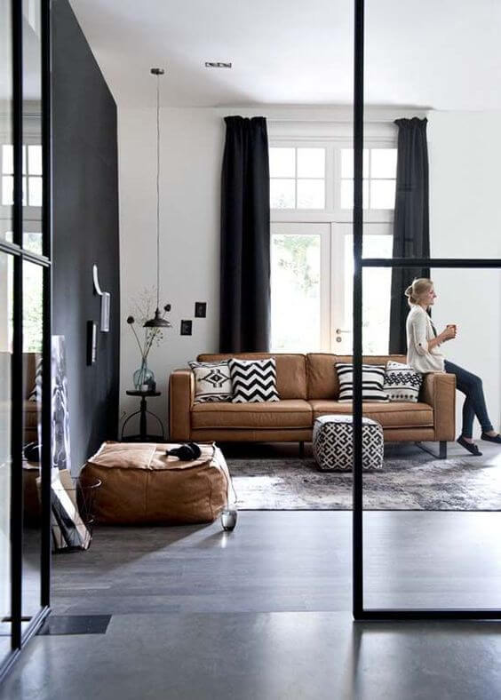 Sala com sofá caramelo de couro e cortina preta