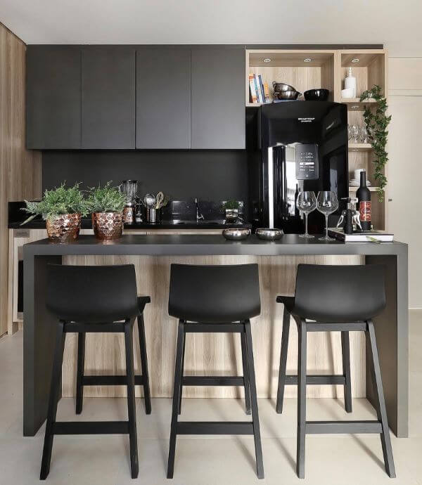 Cozinha americana com geladeira preta e móveis cinza