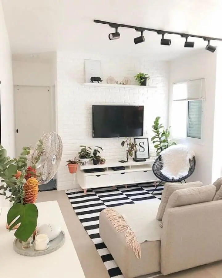 decoração com tapete preto e branco e TV direto na parede de tijolinho branco da sala Foto Casa de Valentina