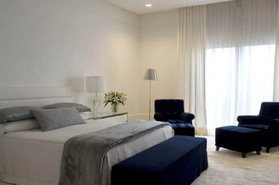 parede branca para quarto de casal amplo decorado com poltrona azul marinho Foto Roberto Migotto