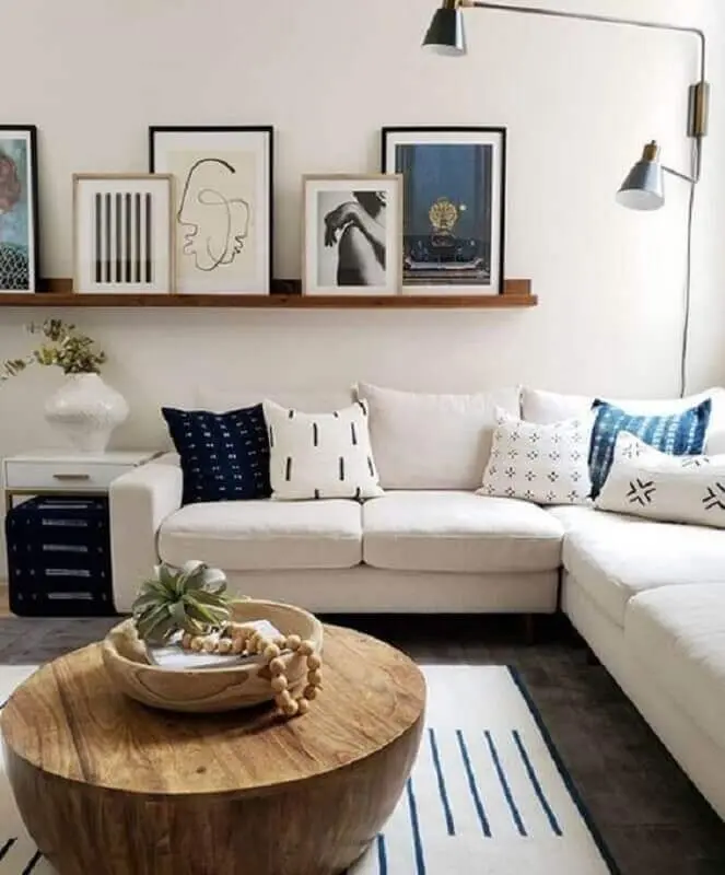 prateleira para quadros sala de estar com mesa de centro de madeira e sofá de canto Foto Jeito de Casa