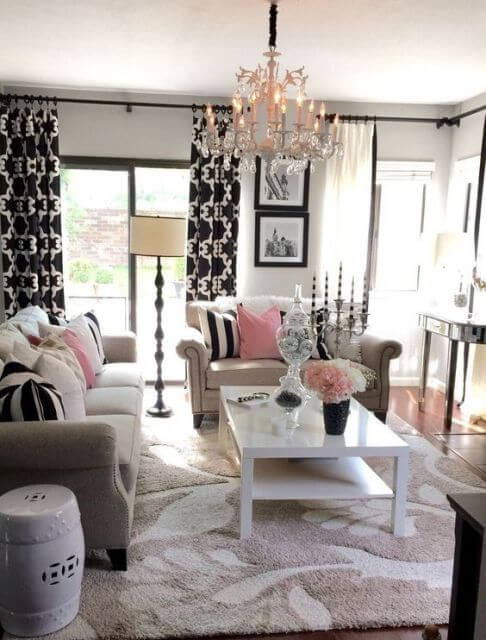 Sala com cortina preta e branca e detalhes cor de rosa