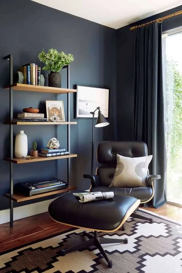 sala decorada com parede azul marinho poltrona confortável e luminária de chão para leitura Foto Pinterest