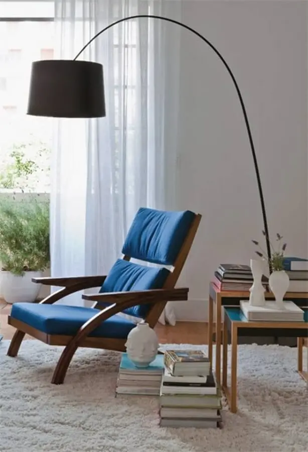 sala decorada com poltrona de madeira estofada azul e luminária de chão para leitura Foto Pinterest