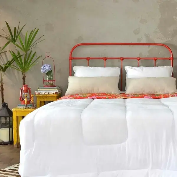 A cabeceira de cama de ferro vermelha traz um toque de cor para o dormitório