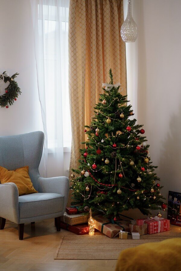 Árvore de Natal pequena para decoração de sala de estar com poltrona cinza Foto Pexels
