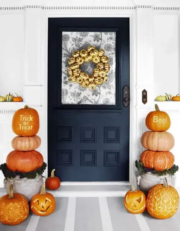 Guirlanda com mini abóbora de halloween pintadas de dourado decoram a porta de entrada
