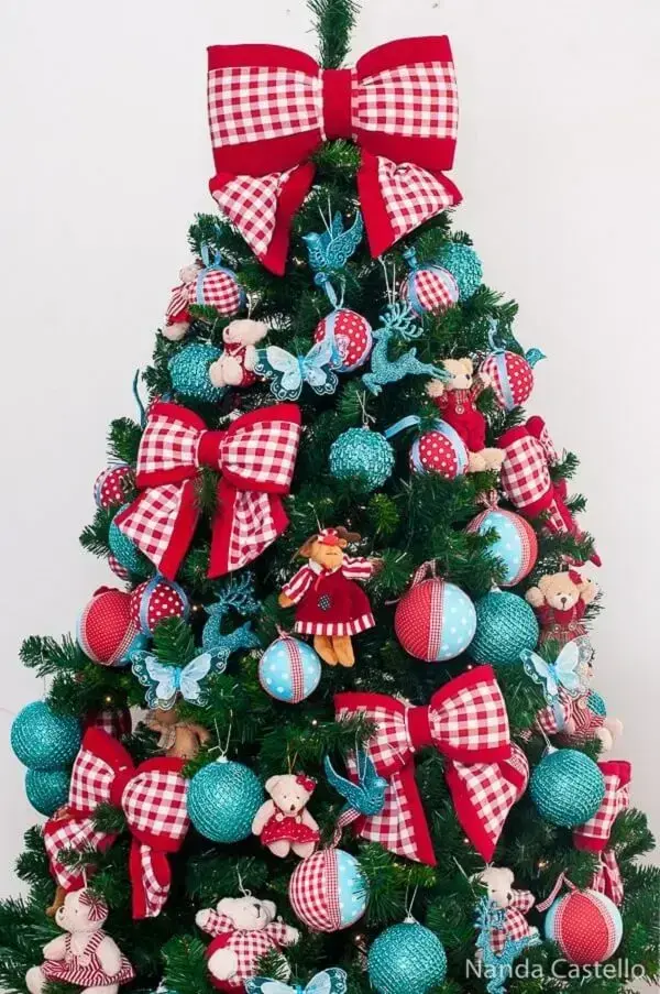 Laços e bolas decoram a árvore de natal azul e vermelha