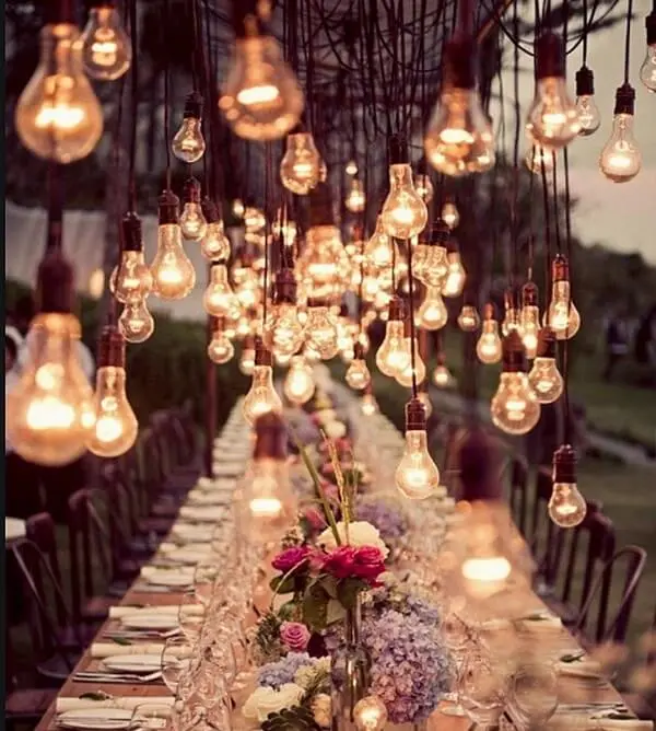 O cordão de luz de lâmpadas decoram toda a extensão da mesa de casamento
