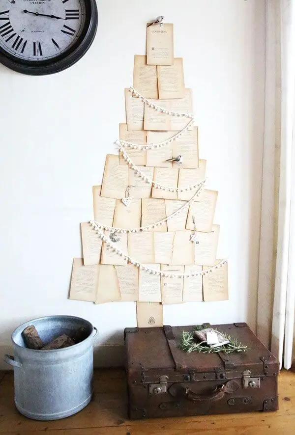 Folhas de livro formando árvore de natal diferente na parede