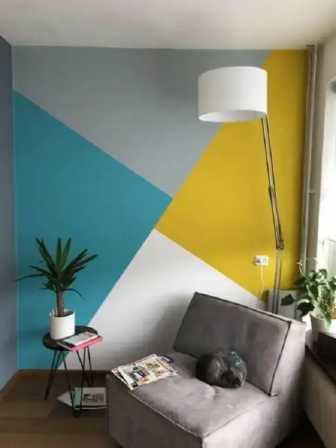 cantinho de leitura decorado com parede com pintura geométrica e poltrona cinza Foto Pinterest