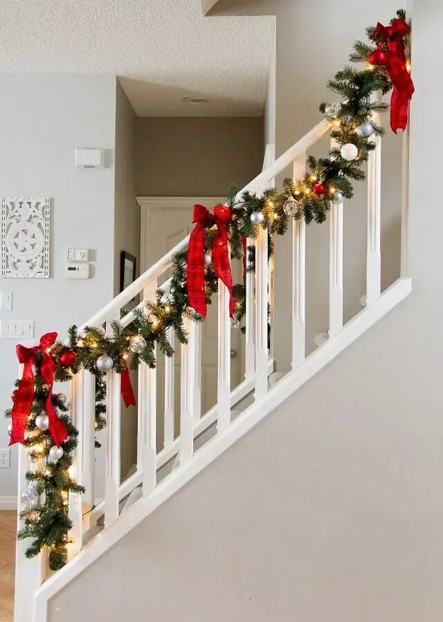 corrimão de escada com festão de Natal decorado com laços bolas e pisca pisca Foto Assetproject