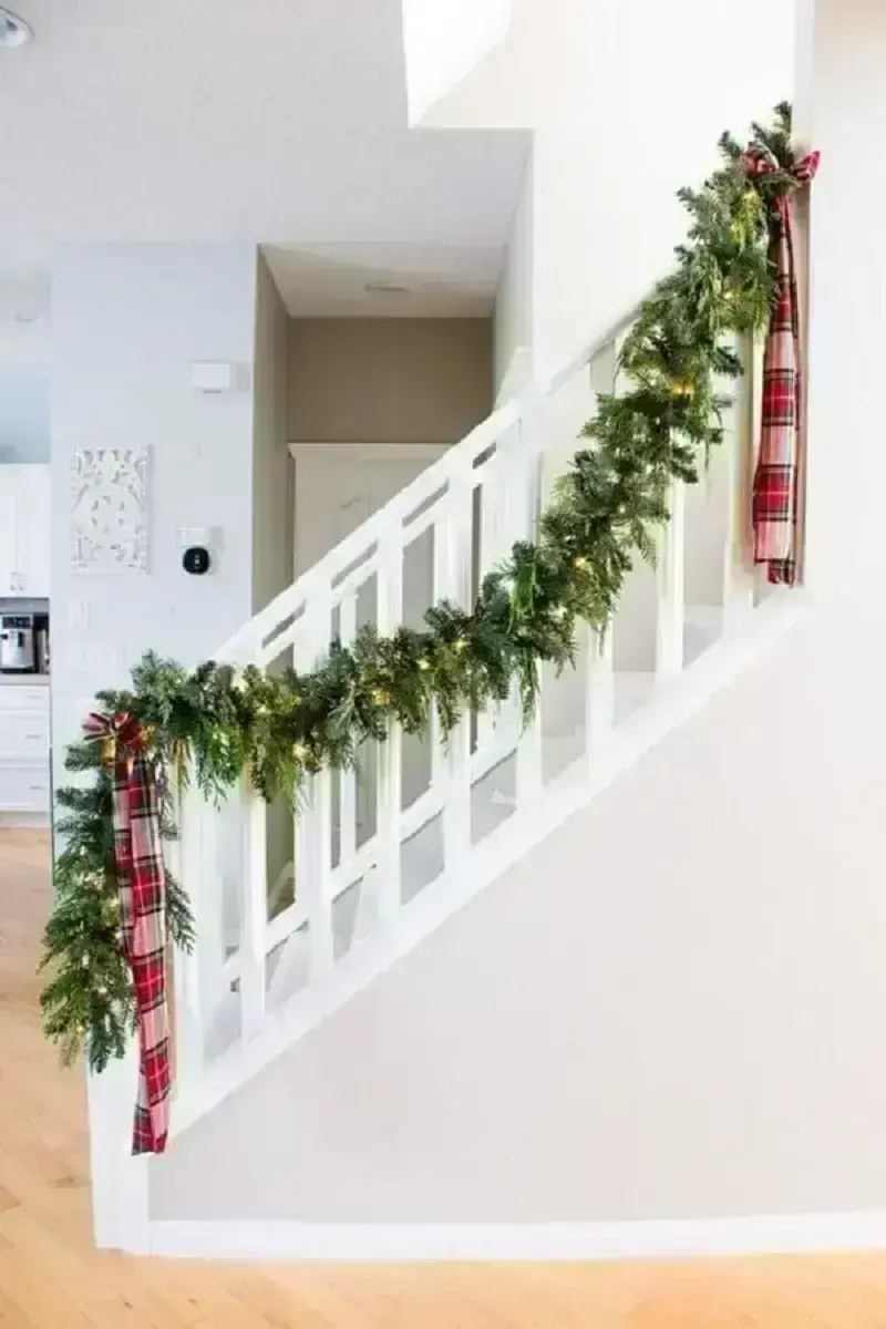 decoração com festão de Natal e laço xadrez para escada branca Foto Dandelion Wishes LLC