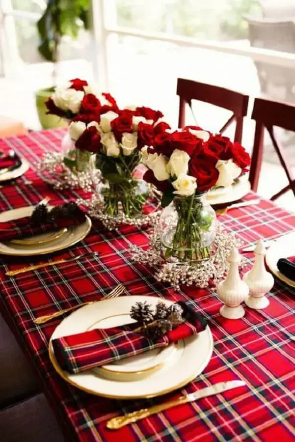 decoração de mesa natalina simples com toalha xadrez vermelha e arranjos de rosas brancas e vermelhas Foto iCasei