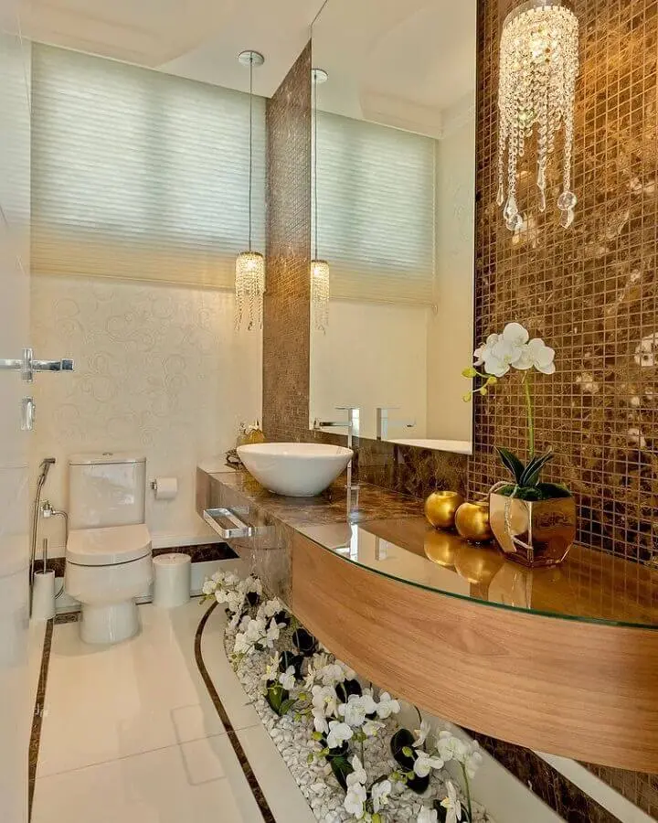 decoração sofisticada com luminária de cristal pendente para bancada de banheiro com pastilhas douradas Foto Iara Kílaris Decoradora