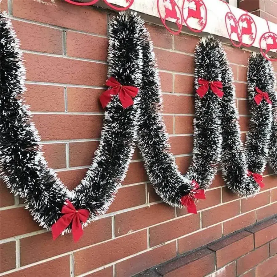 festão de Natal verde com acabamento imitando neve decorado com laços vermelhos Foto Jeito de Casa