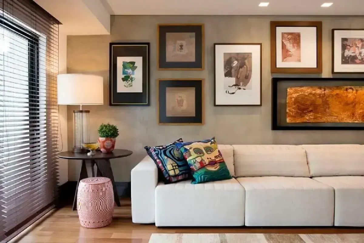 sala moderna e sofisticada decorada com sofá 3 lugares retrátil confortável e parede de cimento queimado com vários quadros Foto Elmor Arquitetura