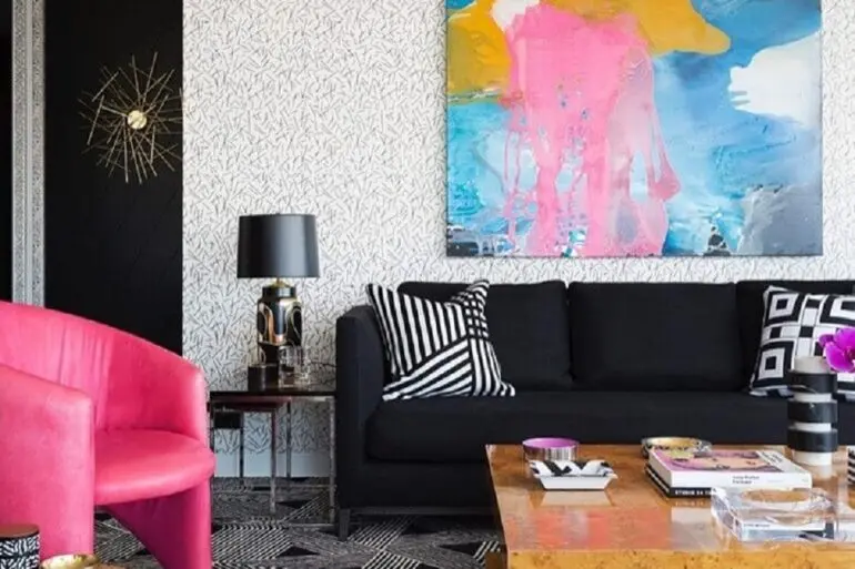 sofá preto para sala decorada com poltrona rosa e quadro grande colorido Foto Greg Natale