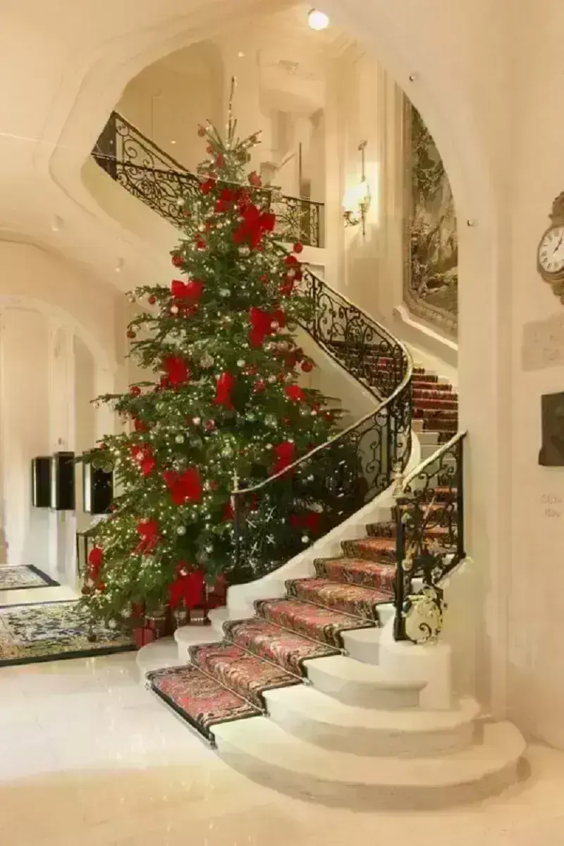 árvore de natal grande com laços vermelhos ao lado de escada Foto The Happy Hideout