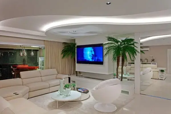 Ambiente com decoração clean com parede espelhada e mesa de centro redonda branca