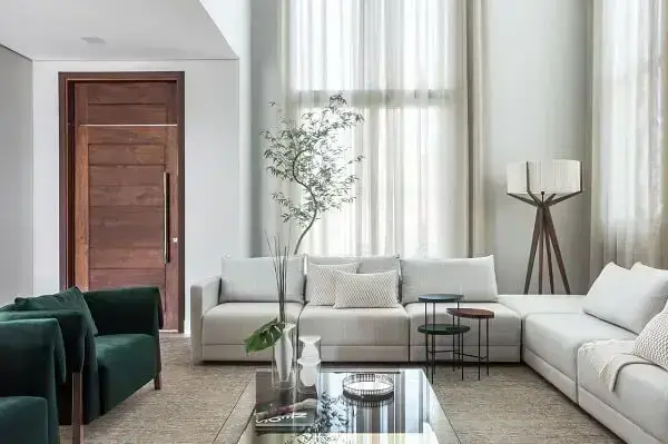 As poltronas verdes trazem um contraste interessante na presença do sofá de linho cru