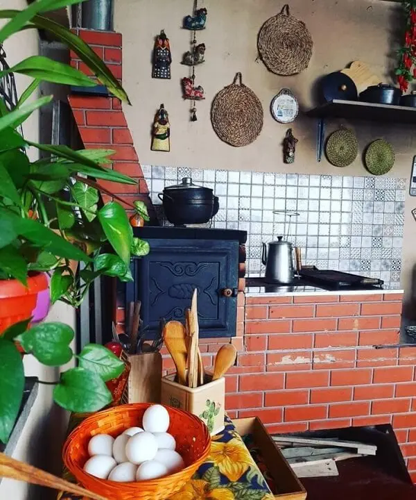 Cozinha pequena com fogão à lenha e diversos utensílios domésticos