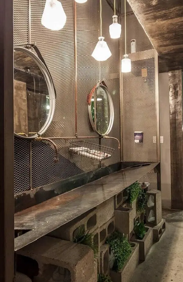 Decoração de barbearia moderna onde o banheiro conta com blocos de concreto e espelho redondo