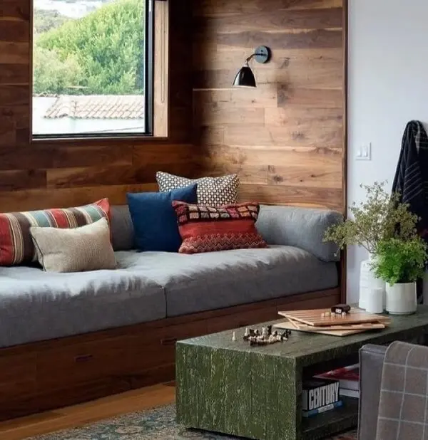 O sofá baú de madeira embutido na parede é uma ótima alternativa para espaços pequenos