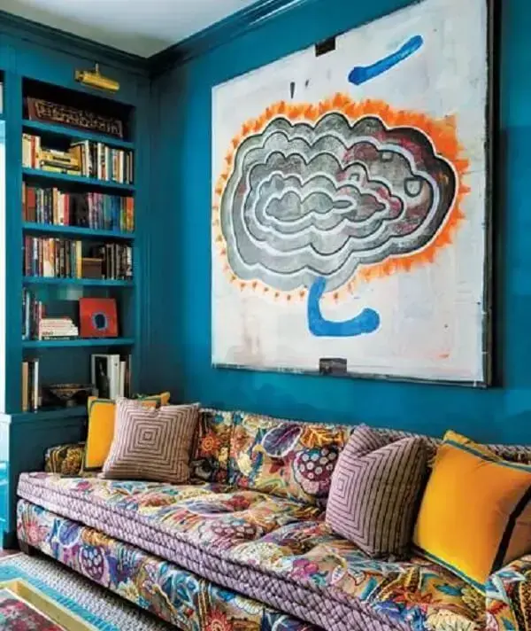 O sofá estampado e o quadro se conectam na decoração