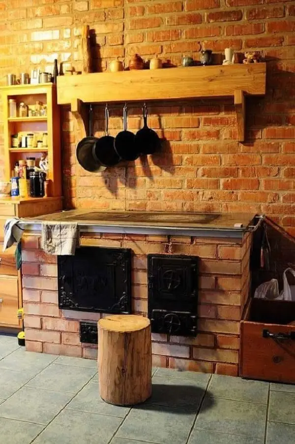 O tijolo à vista deixa a cozinha pequena com fogão à lenha ainda mais aconchegante