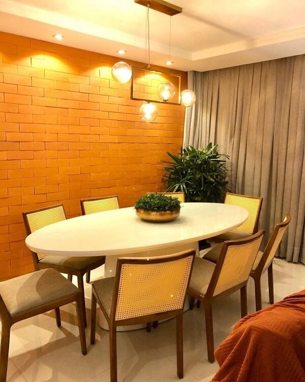 Parede de tijolinho aparente e mesa ovalada decoram a sala de jantar. Fonte: @veraluciabezerraarquitetura