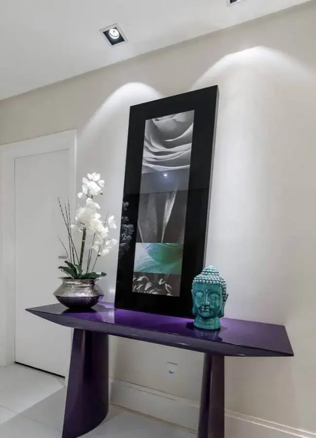 decoração simples para hall de entrada com espelho preto apoiado em aparador roxo Foto Pinterest