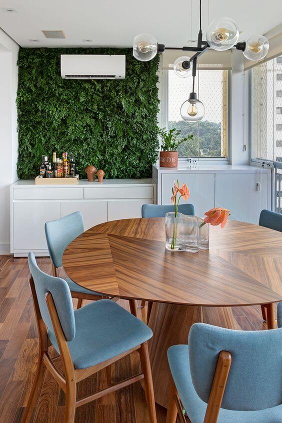 Mesa para varanda gourmet com cadeiras azuis e jardim vertical