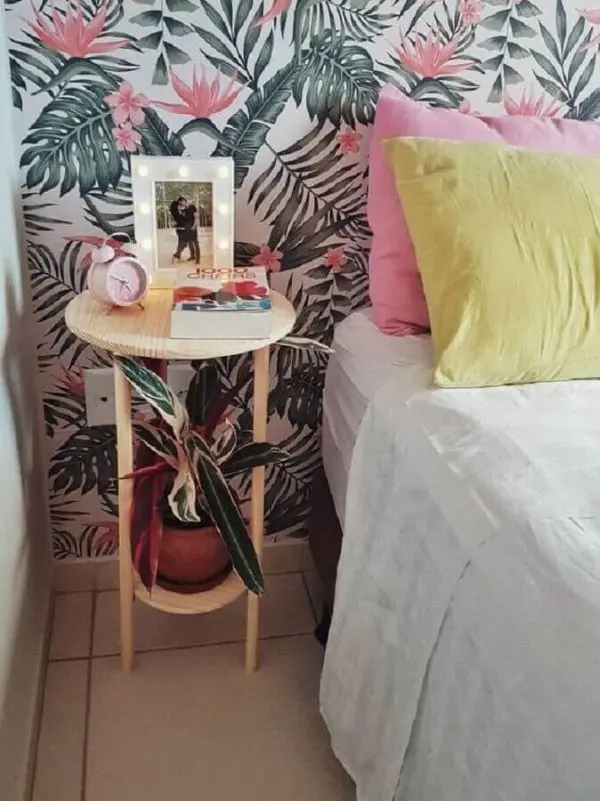 Quarto decorado com papel de parede floral e mesa lateral alta pequena e simples