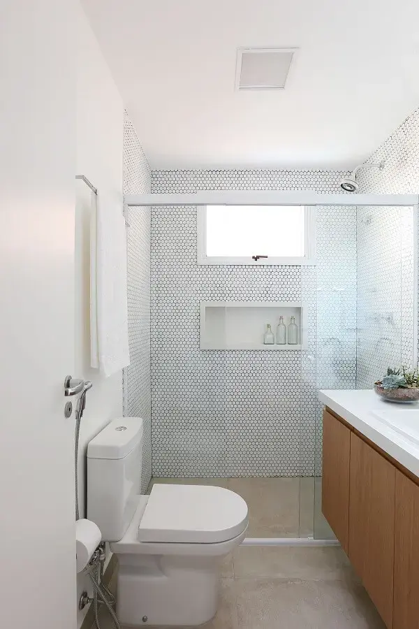 Banheiro clean com chuveiro cromado e balcão com portas de madeira