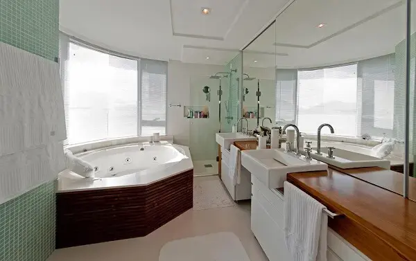 Banheiro com hidromassagem e área de banho com chuveiro cromado quadrado