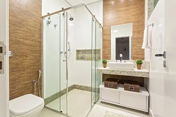Banheiro com lavabo de granito e chuveiro elétrico cromado