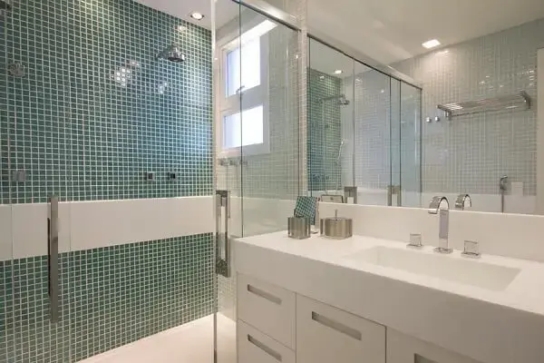 Banheiro com revestimento de pastilha verde e chuveiro elétrico cromado