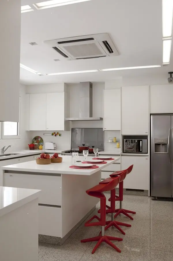 Banqueta giratória vermelha e móveis planejados brancos para a cozinha