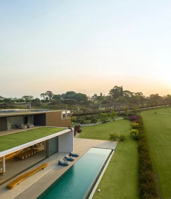 O gramado percorre o entorno das casas de campo com varanda e piscinas
