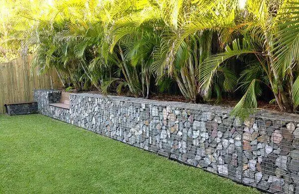 O muro de arrimo de pedra feito com gabiões delimita a área do jardim