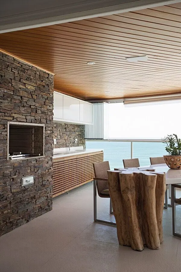 revestimento de pedra para de decoração de varanda gourmet rústica com churrasqueira em apartamento Foto Korman Arquitetos